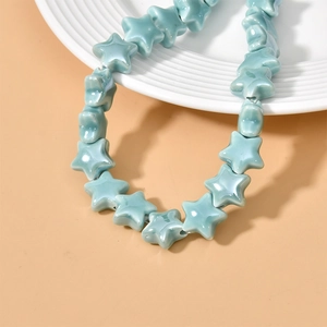 Macro shot of light blue ceramic star beads with glossy finish on a decorative ceramic plate