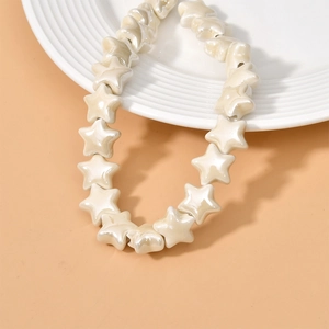 Close-up of cream star-shaped ceramic beads with pearl luster on a white plate