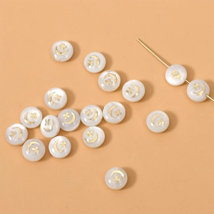 Detalle de cuentas de nácar redondas con luna y trébol dorados para bisutería DIY