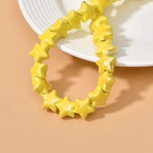 Macro detail of bright yellow star ceramic beads with high-gloss finish on a white plate