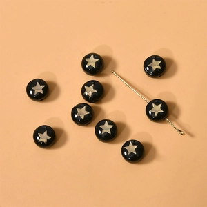 Detalle de cuentas redondas negras con estrellas doradas para creación de joyas DIY