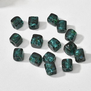 Macro view of translucent dark green cube beads with gold foil textures for DIY jewelry