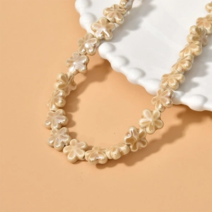Close-up of cream ceramic flower beads with pearl luster on a white wavy ceramic tray