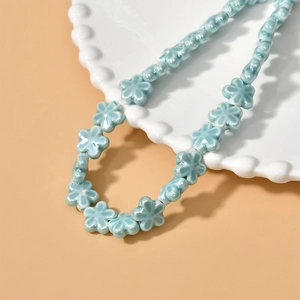 Detail of light blue ceramic flower beads with glossy finish for DIY jewelry making