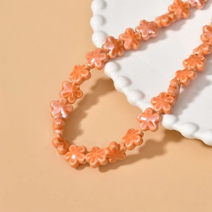 Macro shot of orange five-petal floral ceramic beads with a pearlescent glaze finish