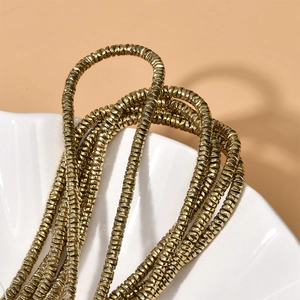 Close-up of golden wave spacer beads on a white shell tray for DIY jewelry making