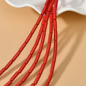 Close-up of vibrant red cylinder turquoise spacer beads in a white ceramic bowl for DIY