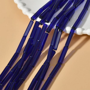 Gros plan de perles tubulaires bleu foncé translucides pour bijoux artisanaux