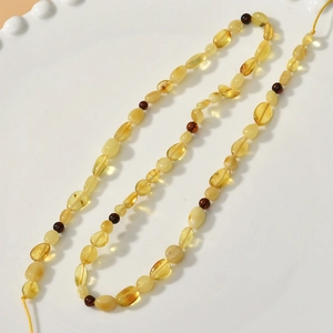 Detail of natural irregular amber beads with polished texture in a white ceramic tray
