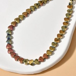 Macro detail of iridescent faceted heart-shaped hematite beads on a white pedestal