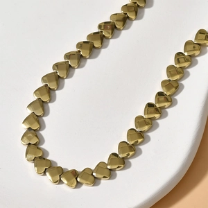 Golden faceted heart-shaped bead necklace with mirror polished finish on white base