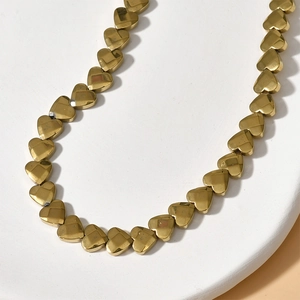 Detail of 6mm faceted gold heart beads arranged in a circular white stone tray