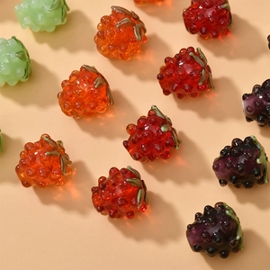 Macro detail of handmade raspberry glass beads with realistic texture and green leaves