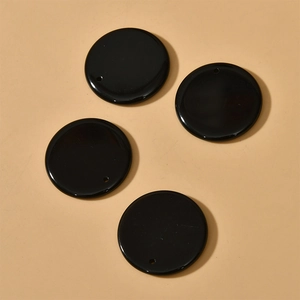 Close-up of four polished black agate 30mm round stone pendants for DIY jewelry making