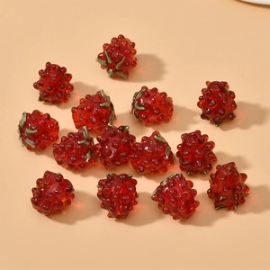 Detailed view of red raspberry glass beads with green leaves for DIY jewelry making