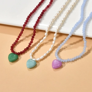 Colorful heart stone pendants on pearl and faceted bead necklaces in a tiered display