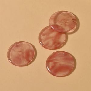Close-up of four 30mm round pink marble texture resin charms with pre-drilled holes