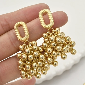 Detail of gold grape bead dangle earrings held by hand to show size and luster