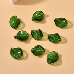 Macro shot of 9 dark green translucent leaf-shaped glass beads for DIY jewelry making