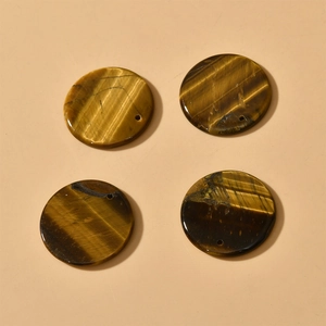 Close-up of polished round tiger eye stone pendants with natural silk luster and pre-drilled holes