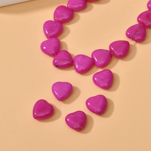 Close-up of vibrant pink heart-shaped natural stone beads with vertical holes for DIY jewelry