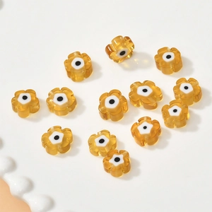Amber flower millefiori beads with evil eye design on a white ceramic tray