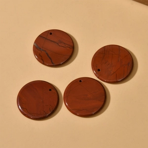 Close-up of four round polished red jasper stone pendants with natural dark veins
