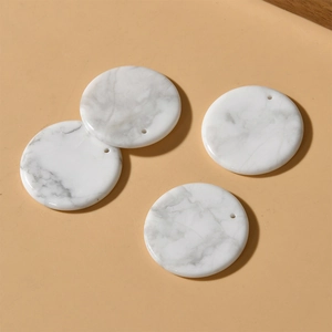 Close-up of four round 30mm white marble stone pendants with natural grey veins for DIY jewelry