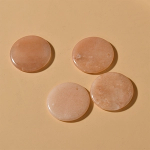 Close-up of four polished 30mm natural orange-pink gemstones with pre-drilled holes for DIY jewelry