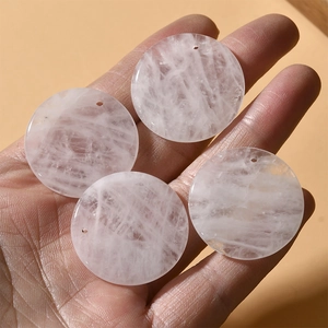 Close-up of four natural rose quartz round gemstone discs with pre-drilled holes for DIY