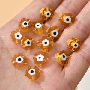 Macro shot of amber flower resin beads with evil eye detail held in hand for DIY jewelry