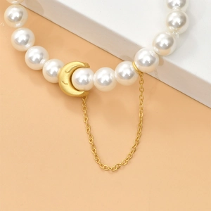 Detail of faux pearl bead with gold matte moon smiley pendant and fine metal chain drop