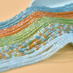 Makro-Detail von 4mm matten quadratischen Glasperlen in zartem Blau, Grün und Orange