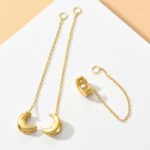 Detailed close-up of matte gold moon pendants and chains on white geometric platforms