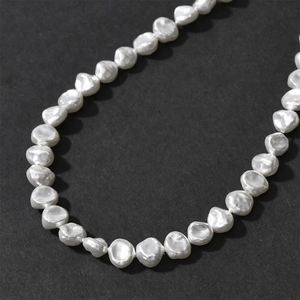 Macro detail of white baroque irregular pearl necklace on dark matte background
