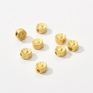 Close-up of eight matte gold flower spacer beads with vertical holes for DIY jewelry