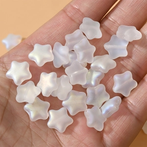Close-up of 12mm frosted AB aurora star glass beads held by hand for DIY jewelry making