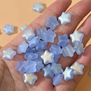 Close-up of 12mm blue matte frosted star beads with iridescent finish held in hand
