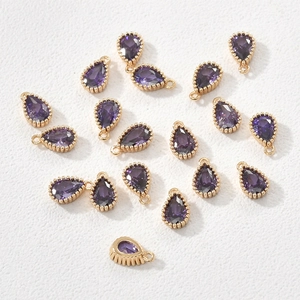 Macro view of purple teardrop zircon charms with 14k gold plated beaded frames for DIY