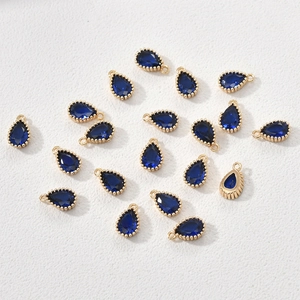 Detail of 14k gold-plated teardrop pendants with deep blue zircon and beaded edges