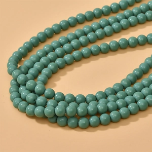 Macro detail of 8mm round teal glass beads for DIY jewelry making and necklaces