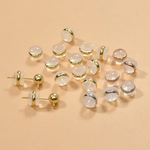 Macro detail of clear silicone earring backs with gold metal ring inserts and stud posts