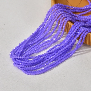 Strands of 3mm faceted lilac glass beads spilling from a ceramic jar for DIY jewelry making