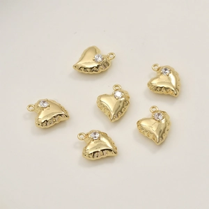 Dettaglio di ciondoli a cuore placcati in oro 14k con zirconia e bordo impunturato