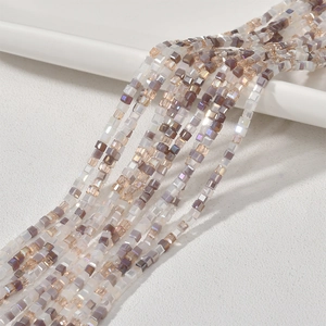 Macro detail of 2mm square crystal beads with iridescent finish on a white ceramic tray