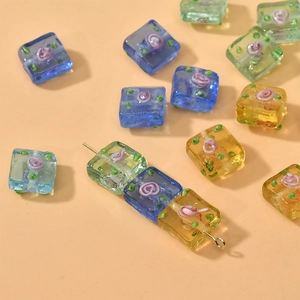 Detailed view of square lampwork beads with rose patterns for DIY jewelry making