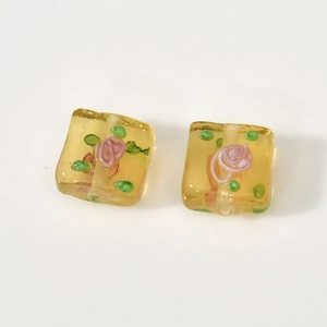 Detail view of square yellow translucent glass flower beads with internal pink rose for DIY