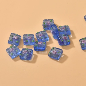 Detail of square blue glass beads with pink spiral flower patterns for DIY jewelry making
