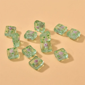 Macro detail of square green glass beads with floral rose pattern for DIY jewelry making