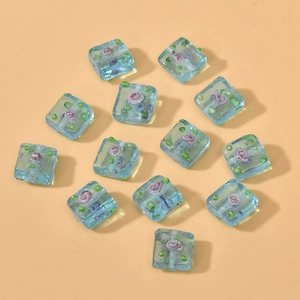 Detail of square glass beads with lampwork flowers for DIY bracelet and necklace making